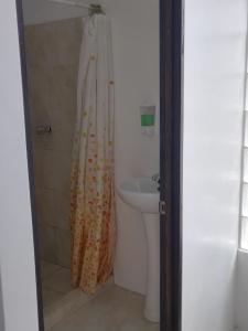 y baño con cortina de ducha y lavamanos. en Lajuela BnB & Hostel, en Alajuela