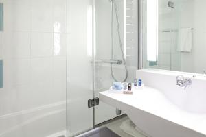 
a bathroom with a sink, mirror and bath tub at Novotel Sheffield Centre in Sheffield
