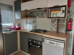 une cuisine avec une cuisinière et un comptoir dans l'établissement MOBIL HOME CAMPING LES VIVIERS 4 ETOILEs, à Lège-Cap-Ferret