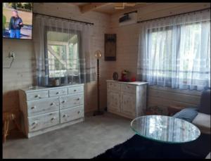 uma sala de estar com uma cómoda e uma mesa de vidro em Domek letniskowy Ania em Pasym