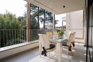 uma varanda com uma mesa de vidro e cadeiras em Casa Corand - Bardolino em Bardolino