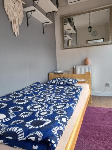 Dormitorio con cama con edredón azul y espejo en tanieSPAnie Rokietnica, en Rokietnica