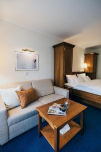 ein Hotelzimmer mit einem Sofa und einem Bett in der Unterkunft Hotel Reindl Suiten & Appartments in Bad Füssing