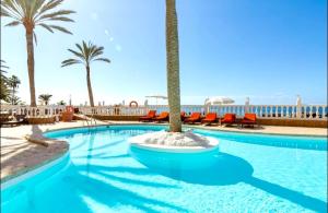 einen großen Pool mit Palmen und Stühlen in der Unterkunft Beach Point Ocean View Suite in Arguineguín