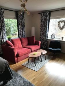 a living room with a red couch and a table at Mysig lägenhet, nära det mesta! in Uddevalla