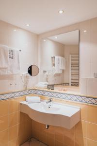 a bathroom with a sink and a mirror at Hotel Reindl Suiten & Appartments in Bad Füssing