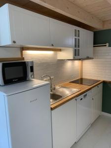 a kitchen with white cabinets and a sink and a microwave at Maisonnette Mimosa H3 avec piscine intérieure chauffée à 400 m de la plage et ménage de fin de séjour compris in Les Sables Vignier