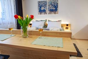 - une table avec deux verres de vin et des fleurs dans l'établissement Studio apartman D7, à Vukovar