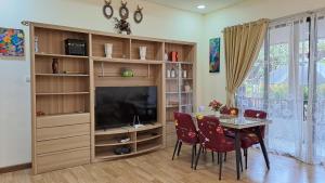 ein Esszimmer mit einem TV, einem Tisch und Stühlen in der Unterkunft Vimala Hills Villa & Resort in Megamendung
