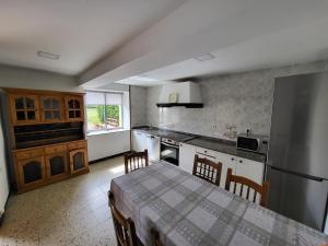a kitchen with a table and a refrigerator and cabinets at O Cabaleiro in Santa Marta de Ortigueira