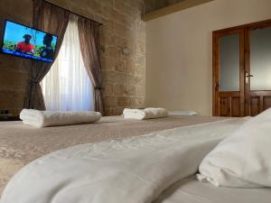 1 dormitorio con 2 camas y TV en la pared en Xemx, en Qala