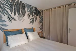 ein Schlafzimmer mit einem Bett mit blauen und weißen Kissen in der Unterkunft Centre du Val André - appart en rez de jardin avec terrasse et jardinet - plage à 150 m in Pléneuf-Val-André