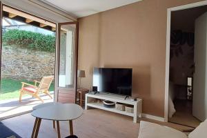 ein Wohnzimmer mit Flachbildfernseher und Tisch in der Unterkunft Centre du Val André - appart en rez de jardin avec terrasse et jardinet - plage à 150 m in Pléneuf-Val-André