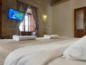 a bedroom with two beds and a tv on the wall at Xemx in Qala