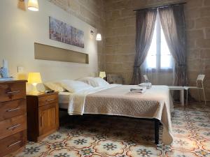 a bedroom with a bed and a dresser and a window at Xemx in Qala