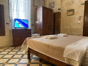 a bedroom with a bed and a tv on a dresser at Xemx in Qala