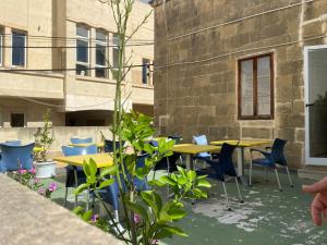 un patio con mesas amarillas, sillas y plantas en Xemx, en Qala