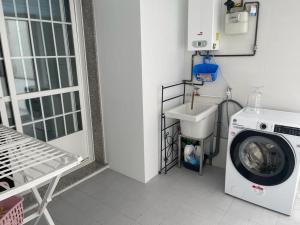 een wasruimte met een wasmachine en een wastafel bij Piso O cruceiro in O Grove