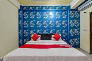 łóżko z czerwonymi poduszkami w niebieskiej sypialni w obiekcie Flagship Baba Guest House w mieście Indirapuram
