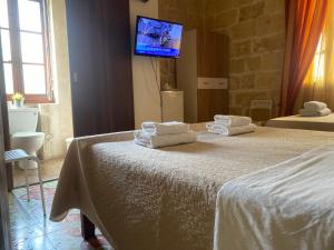 a bedroom with two beds and a tv on the wall at Xemx in Qala
