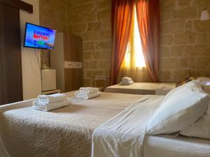 a bedroom with two beds and a tv on a wall at Xemx in Qala