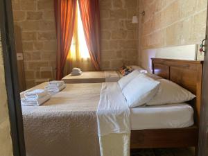 a bedroom with two beds with towels and a window at Xemx in Qala
