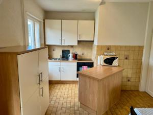 eine kleine Küche mit weißen Schränken und einer Mikrowelle in der Unterkunft Appartement in Couvet