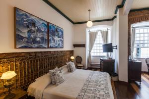 a bedroom with a bed and a painting on the wall at Pousada Solar dos Deuses in Salvador