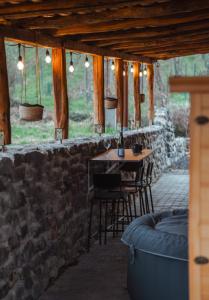 un patio con mesa, sillas y pared de piedra. en Somló Nordic, en Somlószőlős