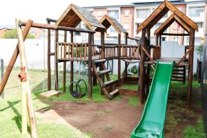 un parque infantil de madera con un tobogán verde y columpios en Cozy Hidden gem in Midrand, en Midrand