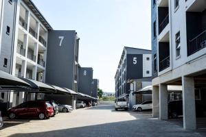 a row of cars parked in a parking lot between buildings at Cozy Hidden gem in Midrand in Midrand