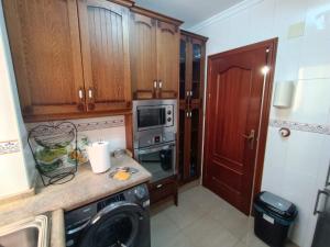 cocina con armarios de madera y lavadora en Apartamento luymar, en Torre de Benagalbón