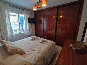 1 dormitorio con 1 cama blanca grande y armario de madera en Apartamento luymar, en Torre de Benagalbón