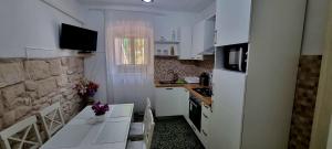 uma cozinha com armários brancos, uma mesa e um micro-ondas em Apartman Marin - Viganj em Viganj