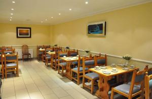 a dining room with wooden tables and chairs at Olympic House Hotel in London