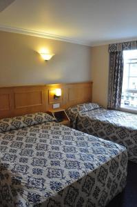a hotel room with two beds and a window at Olympic House Hotel in London