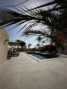 um resort com uma piscina e uma palmeira em Domaine sultana em Awlād ‘Umar