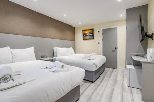 a hotel room with two beds and a sink at Belmont Hotel in London