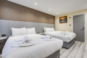 2 Betten in einem Hotelzimmer mit weißen Handtüchern darauf in der Unterkunft Belmont Hotel in London