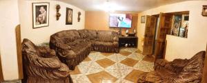 uma sala de estar com um sofá de couro e uma televisão em LA CASA DEL ABUELO em Urubamba