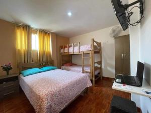 1 dormitorio con 1 cama y escritorio con ordenador portátil en Aristides Inn, en Huarmey