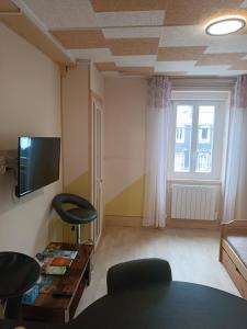 Una sala de estar con un sofá, una mesa y un televisor. en le Mont dore Centre ville appartement, en Le Mont-Dore