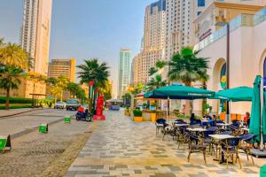 een stadsstraat met tafels, parasols en gebouwen bij Jbr beach walk 2 bedrooms front sea in Dubai