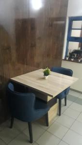 uma mesa de madeira com duas cadeiras azuis à volta em OD-V!CK'S LUXE, Wuse Zone 4, Swimming Pool, Gym, WiFi, 24hr power, security, Dstv em Abuja