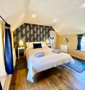 a bedroom with a large bed with blue pillows at Luxury Cottage Dog friendly with Hot Tub in Fairford