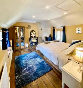 a bedroom with a large bed and a blue rug at Luxury Cottage Dog friendly with Hot Tub in Fairford