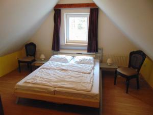 een slaapkamer met een bed met 2 stoelen en een raam bij Holiday House Vitejte doma in Lampertice