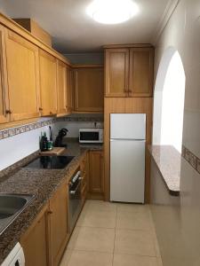 Una cocina con gabinetes de madera y un refrigerador blanco. en Residence Angelina, en San Miguel de Salinas 2 fotos más