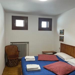 a bedroom with two beds and a chair and two windows at appartamento Cervinia fronte Funivie in Breuil-Cervinia