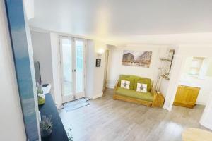 a living room with a green couch and a window at A charming cottage set in Bridgetown Totnes. in Dean